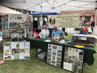 Two people behind a table with the South Jersey Quail Project banner behind them